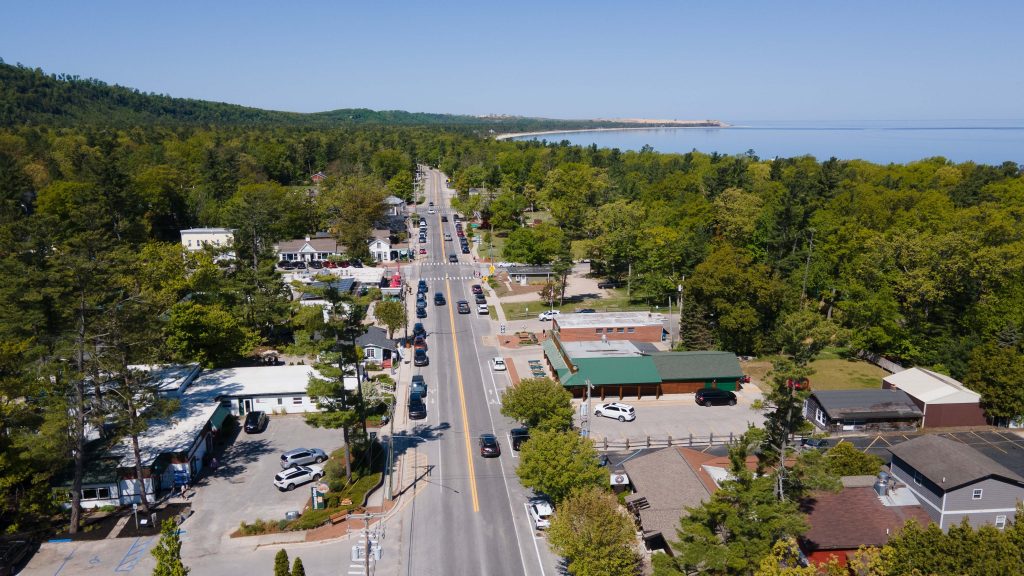 Glen Arbor, Michigan, USA - May 27, 2023: Aerial view of scenic M22 as it runs through downtown Glen Arbor with Sleeping Bear Dunes National Park in the background